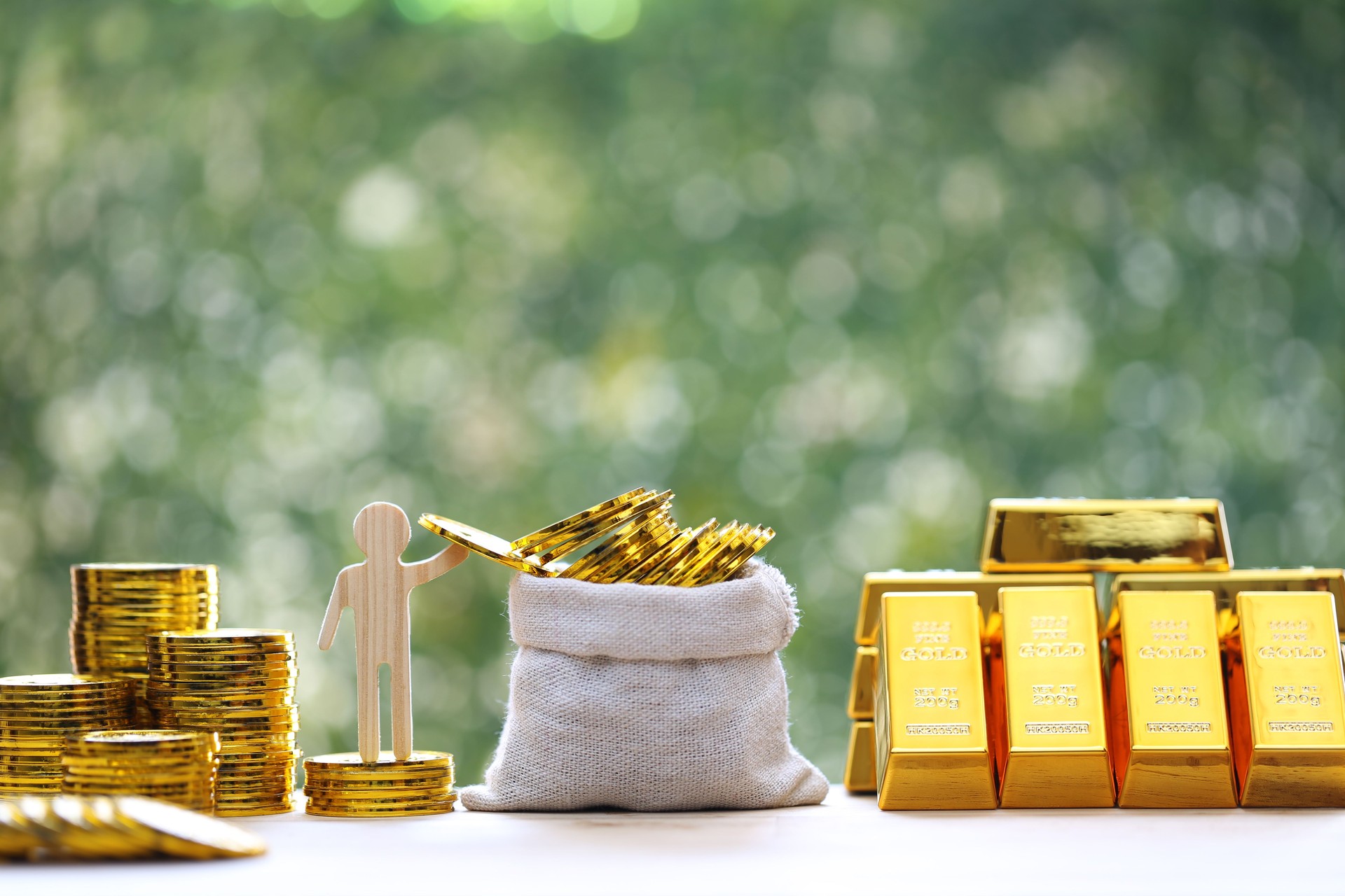 Gold bars and stack of gold coin money in a bag on natural green background,Business investment and financial concept Gold bars and stack of gold coin money in a bag on natural green background,Business investment and financial concept